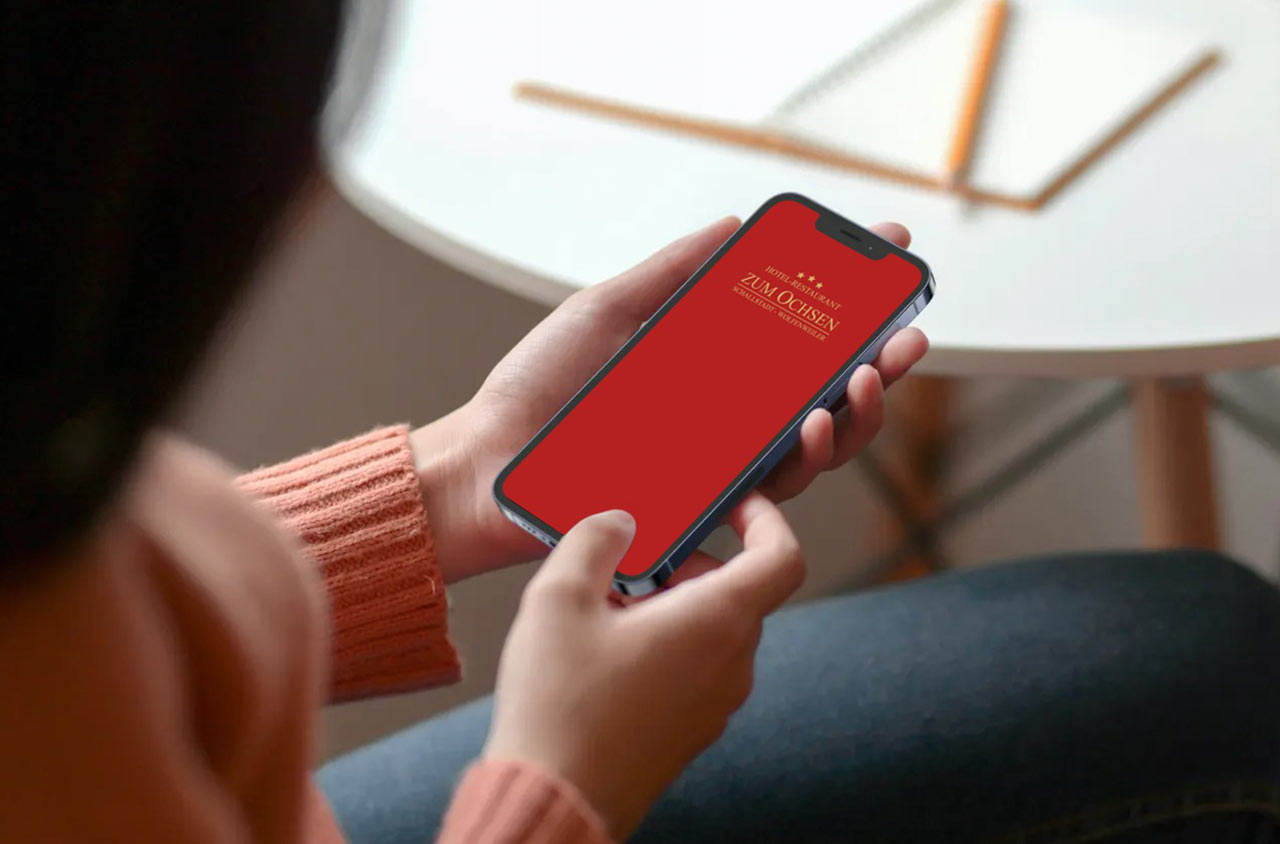 Frau hält Smartphone zur Online-Buchung von Zimmern und Ausflügen